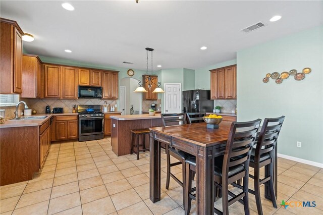 kitchen featuring light tile patterned floors, visible vents, a sink, black appliances, and light countertops