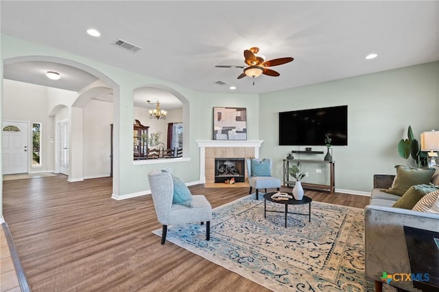 living area with recessed lighting, a tile fireplace, and wood finished floors