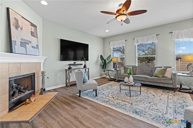 living room featuring wood finished floors, baseboards, recessed lighting, ceiling fan, and a tile fireplace