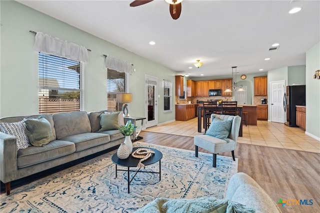 living room with baseboards, visible vents, light wood-style flooring, recessed lighting, and ceiling fan