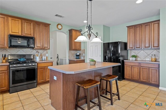 kitchen featuring black appliances, light tile patterned flooring, visible vents, and a center island