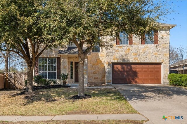 view of front of property featuring a garage, stone siding, a front yard, and driveway