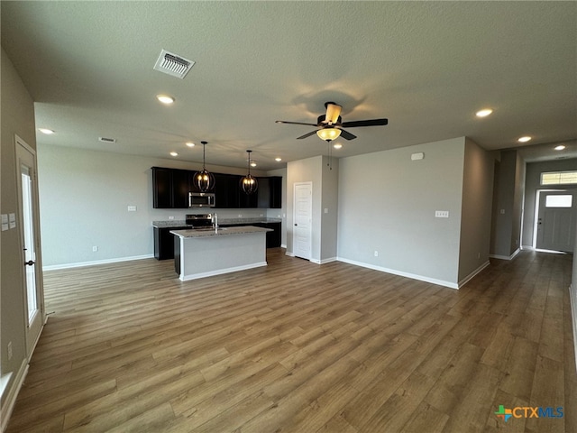 kitchen with dark hardwood / wood-style flooring, a kitchen island with sink, and stainless steel appliances