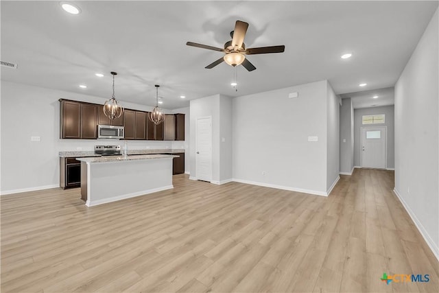 kitchen with stainless steel appliances, pendant lighting, a center island with sink, and light wood-type flooring