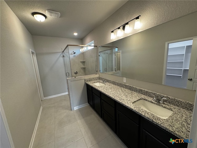 bathroom with walk in shower, vanity, a textured ceiling, and tile patterned floors