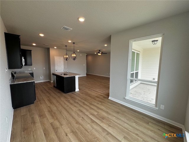 kitchen featuring stainless steel appliances, a center island with sink, sink, ceiling fan, and hardwood / wood-style floors