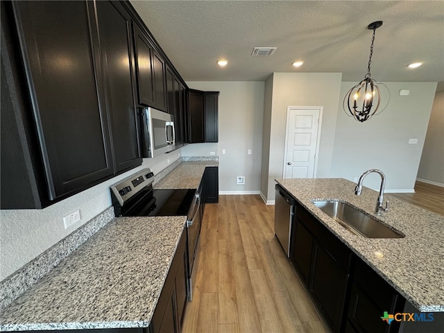 kitchen featuring an island with sink, sink, light hardwood / wood-style flooring, and appliances with stainless steel finishes