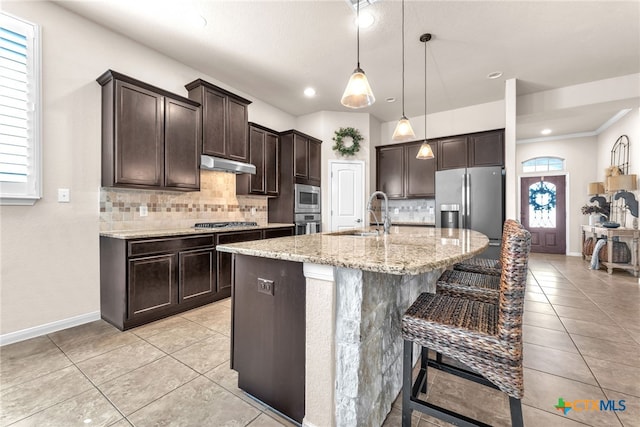 kitchen with sink, decorative light fixtures, dark brown cabinets, appliances with stainless steel finishes, and a kitchen island with sink