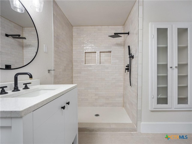 bathroom featuring tiled shower and vanity