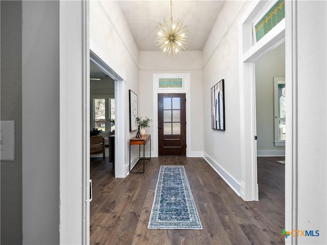 foyer with baseboards, dark wood-type flooring, and a notable chandelier