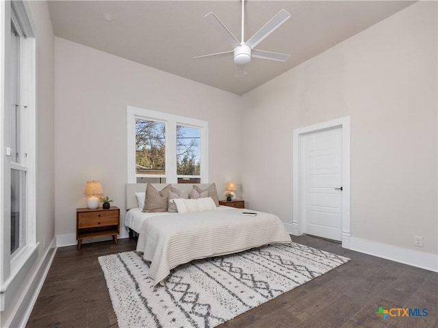 bedroom with dark wood finished floors, a ceiling fan, and baseboards