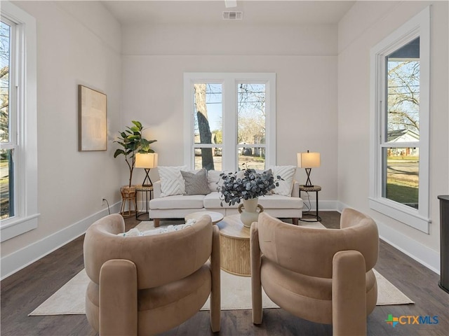 living room featuring visible vents, plenty of natural light, dark wood-type flooring, and baseboards