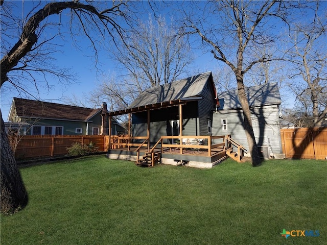 rear view of property featuring a deck, a yard, and a fenced backyard