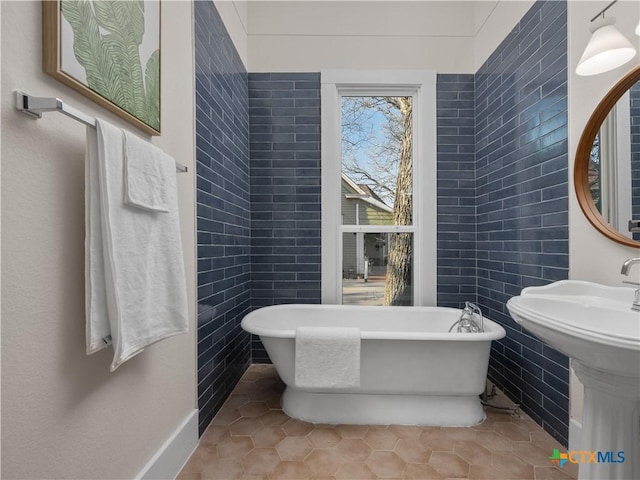 bathroom with tile patterned floors, a freestanding bath, and tile walls