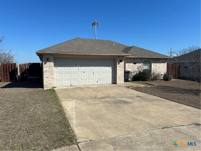 view of front of house with driveway, a garage, a shingled roof, fence, and brick siding