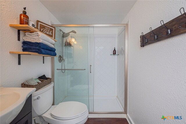 3938 Surfside Blvd Unit 3116, Corpus Christi, TX 78402 - full bathroom featuring toilet, vanity, a stall shower, a textured wall, and wood finished floors
