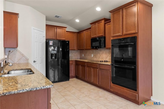 kitchen featuring lofted ceiling, sink, black appliances, light stone countertops, and decorative backsplash