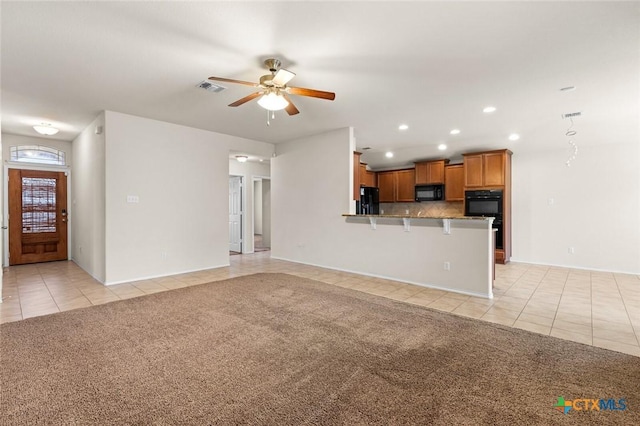 unfurnished living room featuring light carpet and ceiling fan