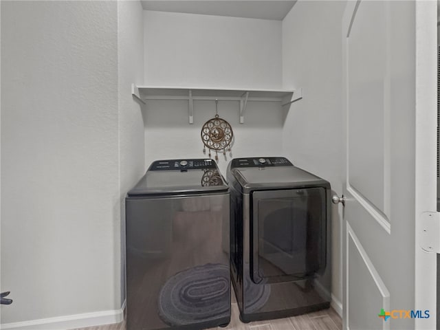 laundry area with light wood finished floors, laundry area, separate washer and dryer, and baseboards