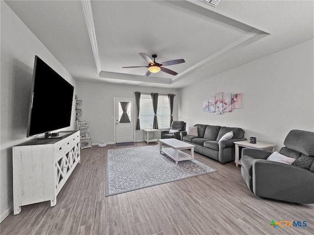 living room featuring visible vents, baseboards, a raised ceiling, ceiling fan, and wood finished floors