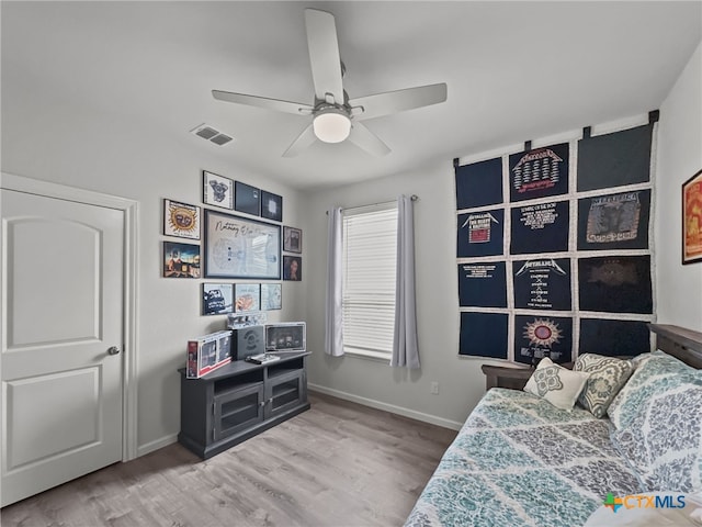 bedroom featuring a ceiling fan, visible vents, baseboards, and wood finished floors