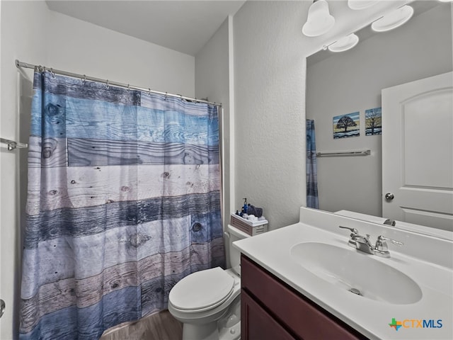 bathroom featuring curtained shower, vanity, toilet, and wood finished floors