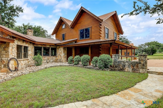 view of front of house featuring stone siding, a chimney, log siding, metal roof, and a front lawn