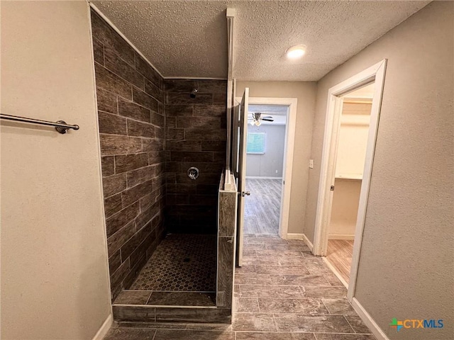 bathroom with tiled shower and a textured ceiling