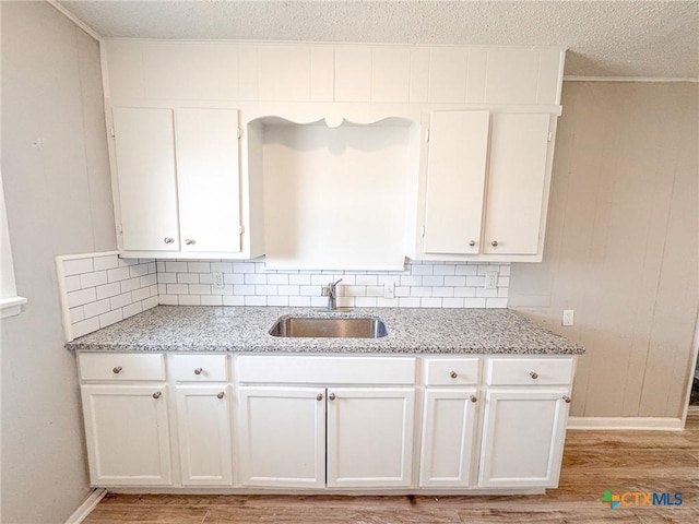 kitchen with white cabinetry, sink, and light stone counters