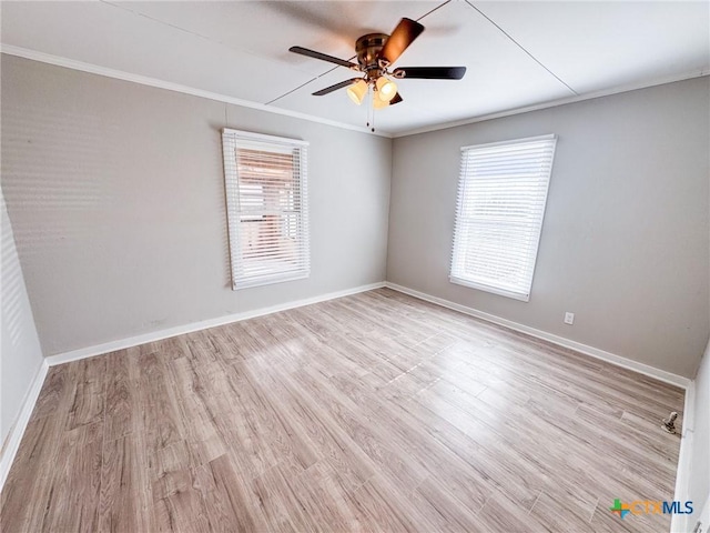 empty room featuring crown molding, light hardwood / wood-style flooring, and a wealth of natural light