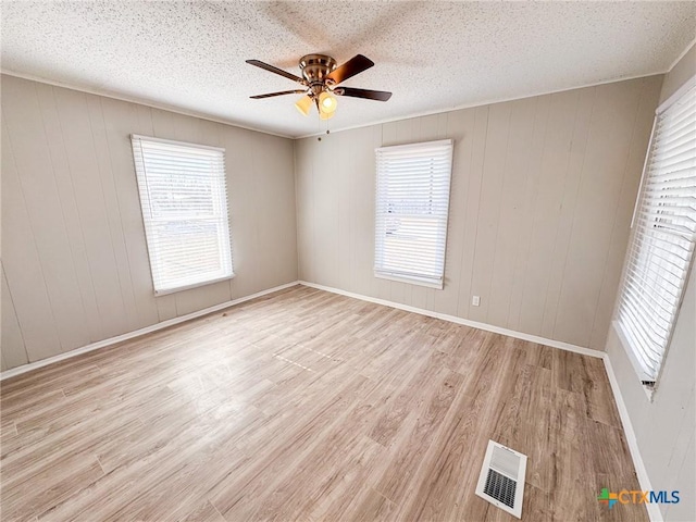 empty room with a healthy amount of sunlight, light hardwood / wood-style floors, and a textured ceiling