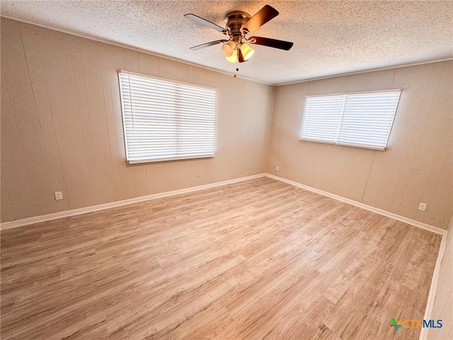 spare room with a textured ceiling, ceiling fan, and light wood-type flooring