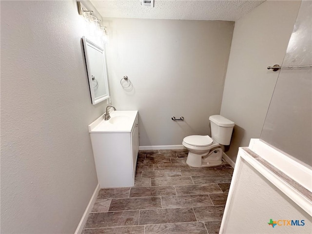 bathroom with vanity, toilet, and a textured ceiling