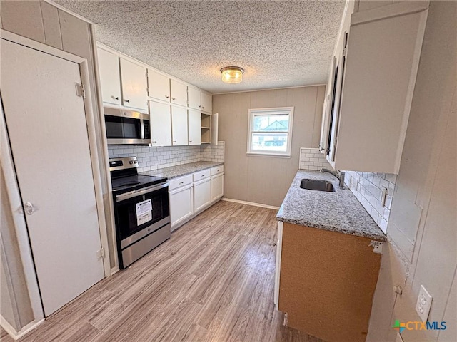 kitchen with white cabinetry, appliances with stainless steel finishes, sink, and light hardwood / wood-style flooring