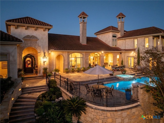 back of property with a pool with connected hot tub, a tile roof, a patio, and stucco siding