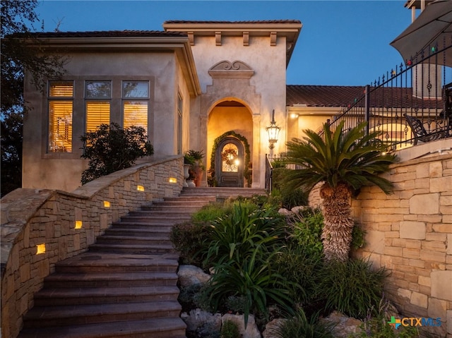 entrance to property with fence and stucco siding