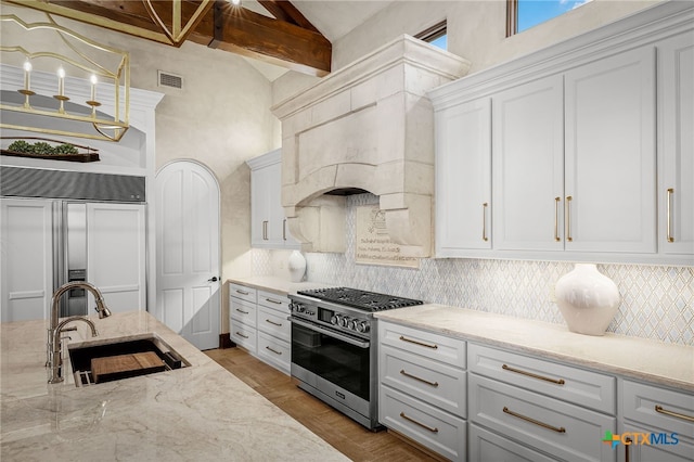 kitchen with high end appliances, tasteful backsplash, visible vents, lofted ceiling with beams, and a sink