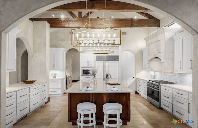 kitchen featuring tasteful backsplash, a sink, beamed ceiling, and built in appliances