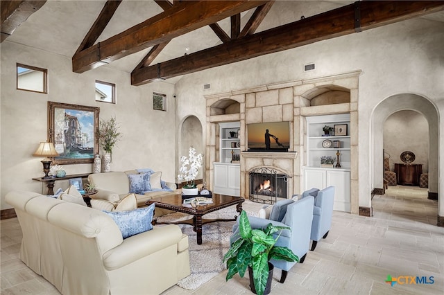 living area featuring arched walkways, beam ceiling, a fireplace, visible vents, and high vaulted ceiling