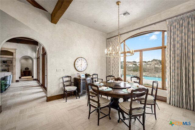 dining space with a high ceiling, visible vents, a notable chandelier, and baseboards