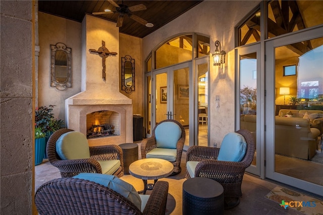 view of patio / terrace featuring a warm lit fireplace and ceiling fan