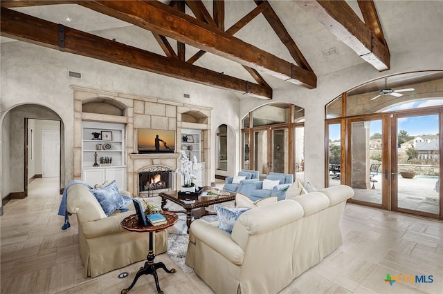 living area featuring high vaulted ceiling, visible vents, a premium fireplace, and arched walkways