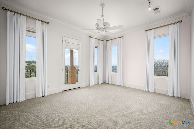 carpeted spare room with a ceiling fan, visible vents, crown molding, and baseboards