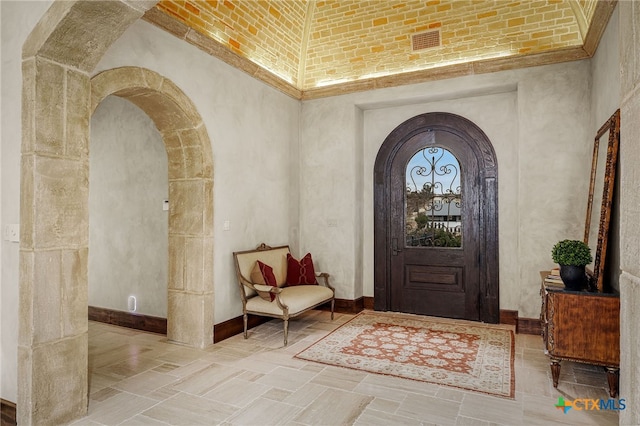 foyer with arched walkways, baseboards, visible vents, and a high ceiling