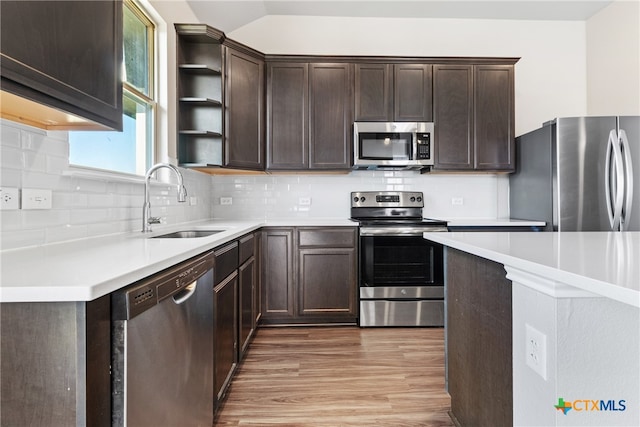 kitchen with sink, stainless steel appliances, lofted ceiling, decorative backsplash, and light wood-type flooring