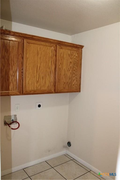 washroom with electric dryer hookup, cabinets, light tile patterned flooring, and washer hookup