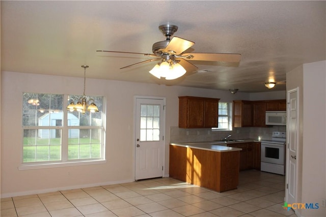 kitchen featuring pendant lighting, white appliances, tasteful backsplash, light tile patterned flooring, and kitchen peninsula