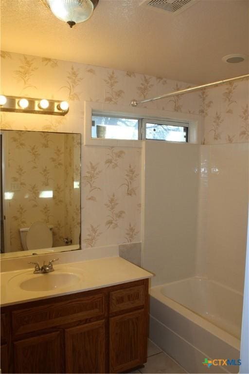 full bathroom featuring tile patterned floors, a textured ceiling, toilet, shower / tub combination, and vanity