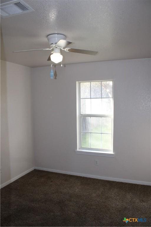 unfurnished room with ceiling fan, a textured ceiling, and dark colored carpet