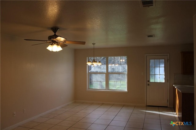 interior space featuring light tile patterned floors, ceiling fan with notable chandelier, and a textured ceiling